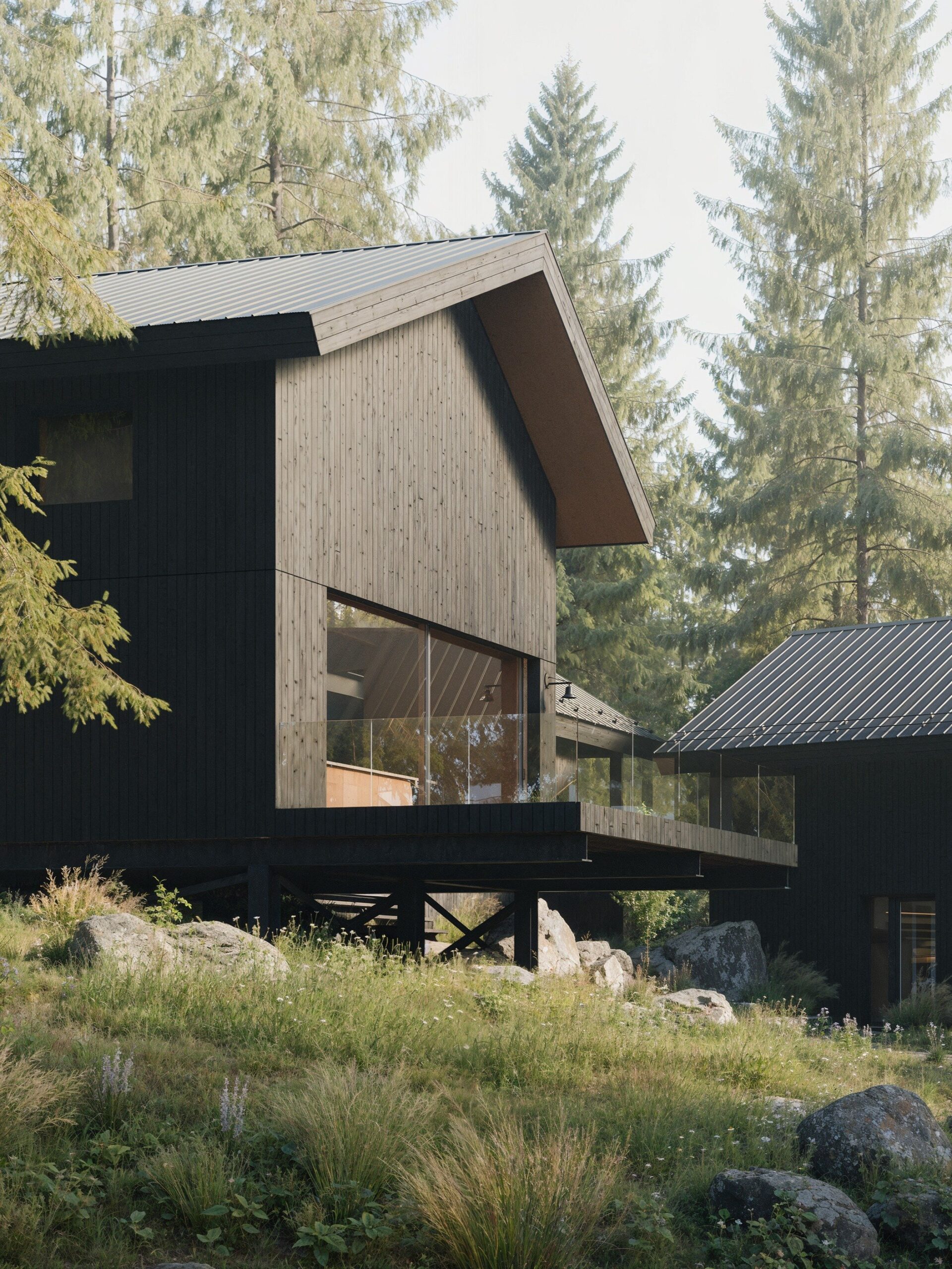 A modern black wooden cabin with a sloped metal roof and large glass windows, elevated on stilts with a glass-railing deck, set in a forested area surrounded by tall pine trees, rocks, and wild grasses. Design in collaboration with Altruist Built and CABN.